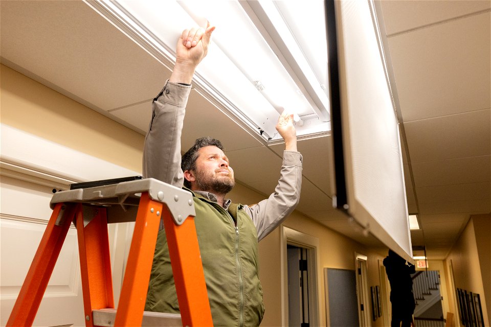 Shane Henning, electrician, installing new LED bulbs