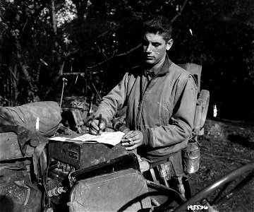 SC 195536 - Lt. William S. Battersby, Nanuet, N.Y., Divisional Artillery Survey Officer, uses his vehicle as a polling booth. 2 October, 1944. photo