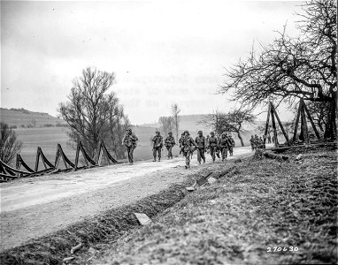 SC 270630 - U.S. Seventh Army infantrymen move past a destroyer barrier made of steel rails in the Altheim Area, Germany, as they press new 7th Army attack.