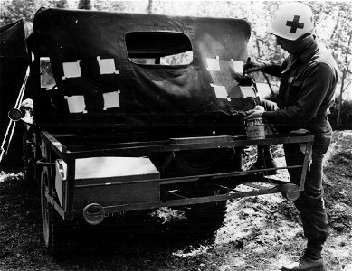SC 374711 - Tec 5 Hugo P. Angel, Dubuque, Iowa, paints red cross on his jeep in St. Nazaire Sector, France. He is a medic attached to a Field Artillery battalion. photo