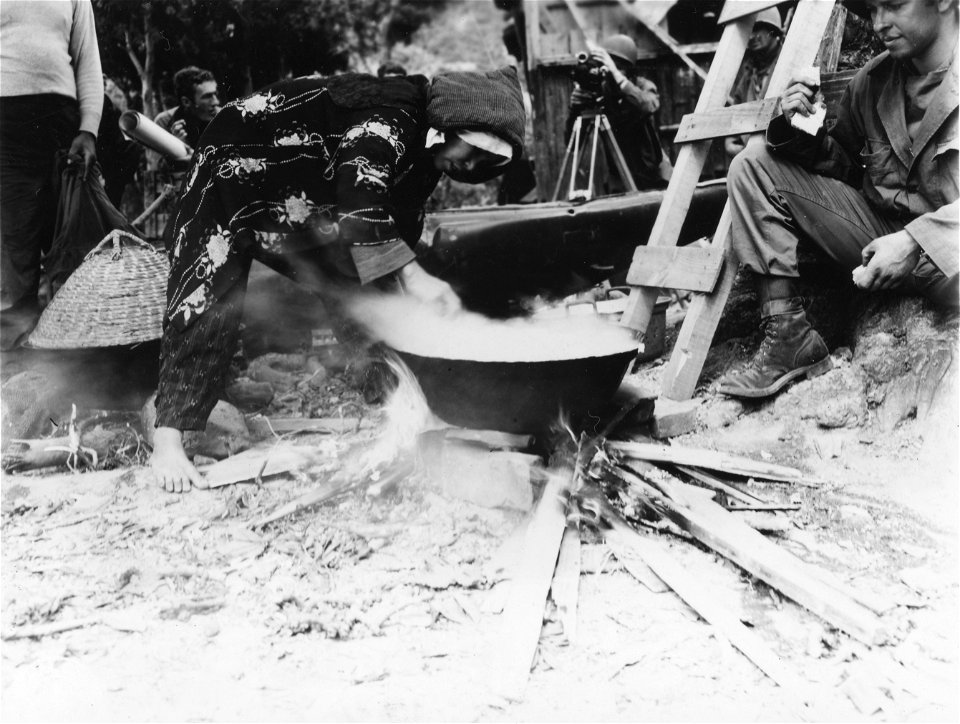 SC 405060 - Native Zamami woman prepares rice in front of municipal buildings for civilians who returned to town after American occupation.