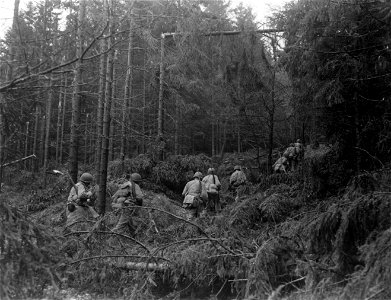 SC 270813 - First U.S. Army infantrymen start through heavy woods on way to attack German-held barracks near Siegen, Germany. 6 April, 1945.