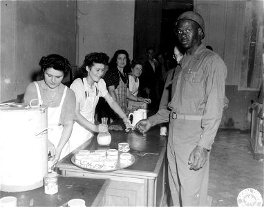 SC 329721 - At the newly opened Red Cross club in Cherbourg. Cpl. Charles C. Murphyel, of Brooklyn, N.Y., gets his share of Yankee doughnuts and coffee. Girls are French Red Cross volunteers. 29 July, 1944. photo