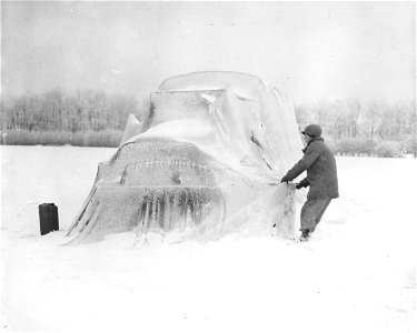 SC 199077 - Pvt. Floyd A. Pilcheo, of Calhoun, Ga., a member of an anti-aircraft unit adjusts the white camouflage net over a 2½ ton truck. 8 January, 1945. photo