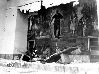 SC 374649 - L-R: Sgt. R.L. Enlow, Deucharis, Ind., and Pvt. Earl Honoker, Bluefield, Va., looking at mural showing Mussolini and farm workers inside the farmers bldg. 25 May, 1944. Littoria area, Italy.