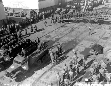 SC 329859 - Helmeted WACs march down the gangplank of transport that has brought them to North African port. Army trucks wait to take them to a nearby transit camp. 10 January, 1944.