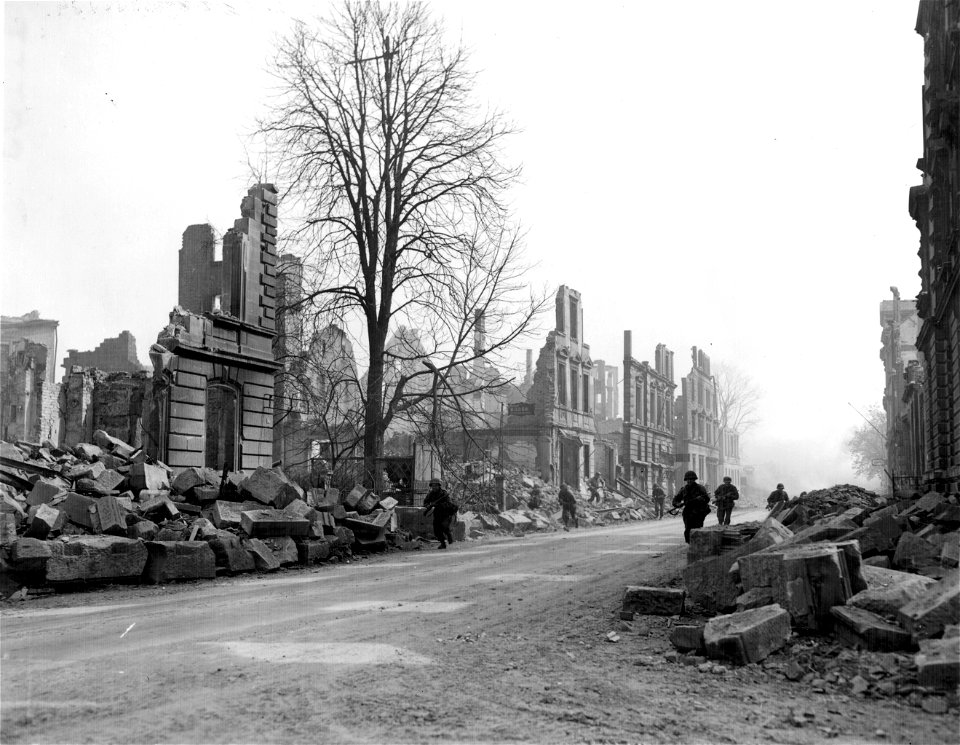 SC 335307 - Infantrymen run through streets of Heilbronn, Germany, near former bridge site, while heavy concentration of German nebelwerfer, artillery and small arms fire continually rake this section of town.