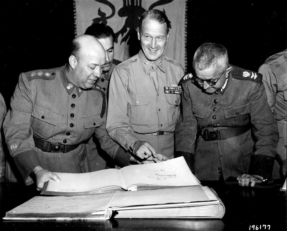 SC 196177 - Maj. Gen. Eurico Jaspar Dutra, Brazilian Minister of war, Maj. Gen. Mascarenhas De Moraes, C.G. B.E.F., and Brig. Gen. E.E. Hume, AMG, Fifth Army, look at a page in golden book containing Hitler’s signature.