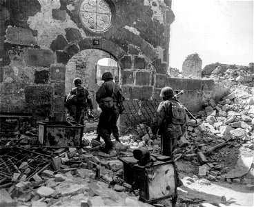 SC 270647 - Infantrymen move through small archway in buildings filled with rubble. They are clearing out of the tunnels and cellars of the houses in the center of town. photo