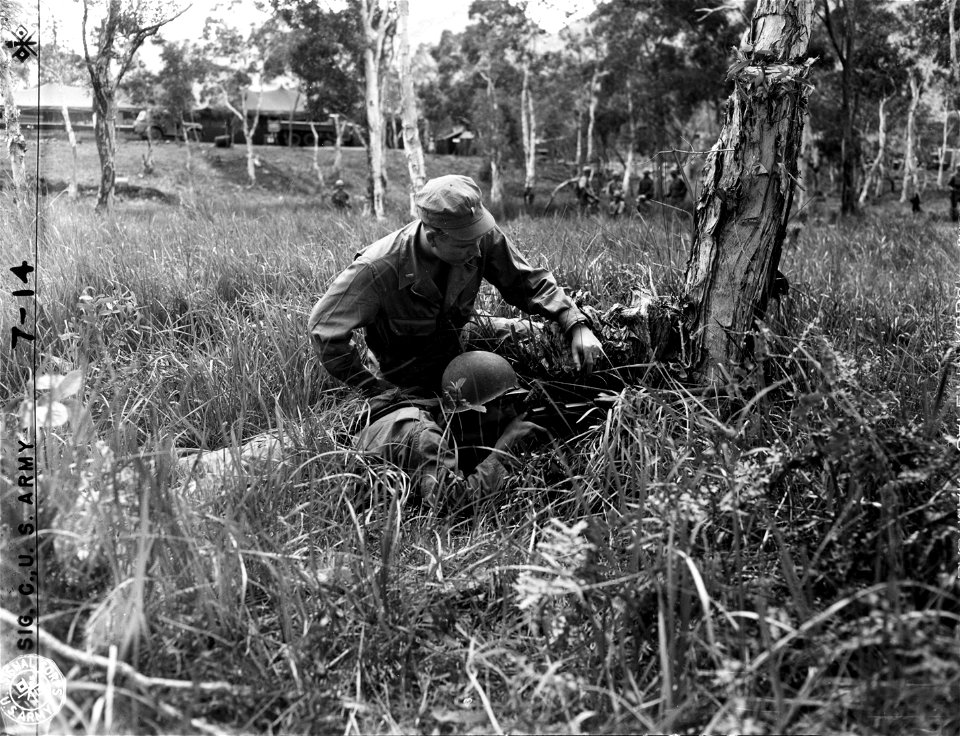 SC 364578 - Lt. George Reed, Chicago, Ill., instructing Pvt. Donald J. Bartosh, Jackson, Minn., in the proper method of firing from behind a tree, during class on Cover and Concealment.