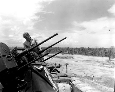 SC 364576 - Pfc. G. Harris of the 951st AA and AW Bn. loading a multiple machine gun, one of the many gun positions guarding the bomber and fighter strips on Bougainville.