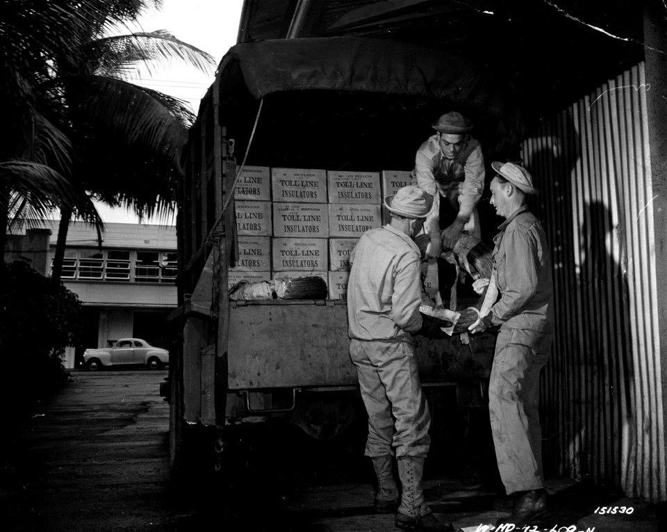 SC 151530 - Cpl. Vincent Harvey and Pvt. Fred Scott, also Cpl. Ed Range unload the material from the supply truck for the line construction. photo