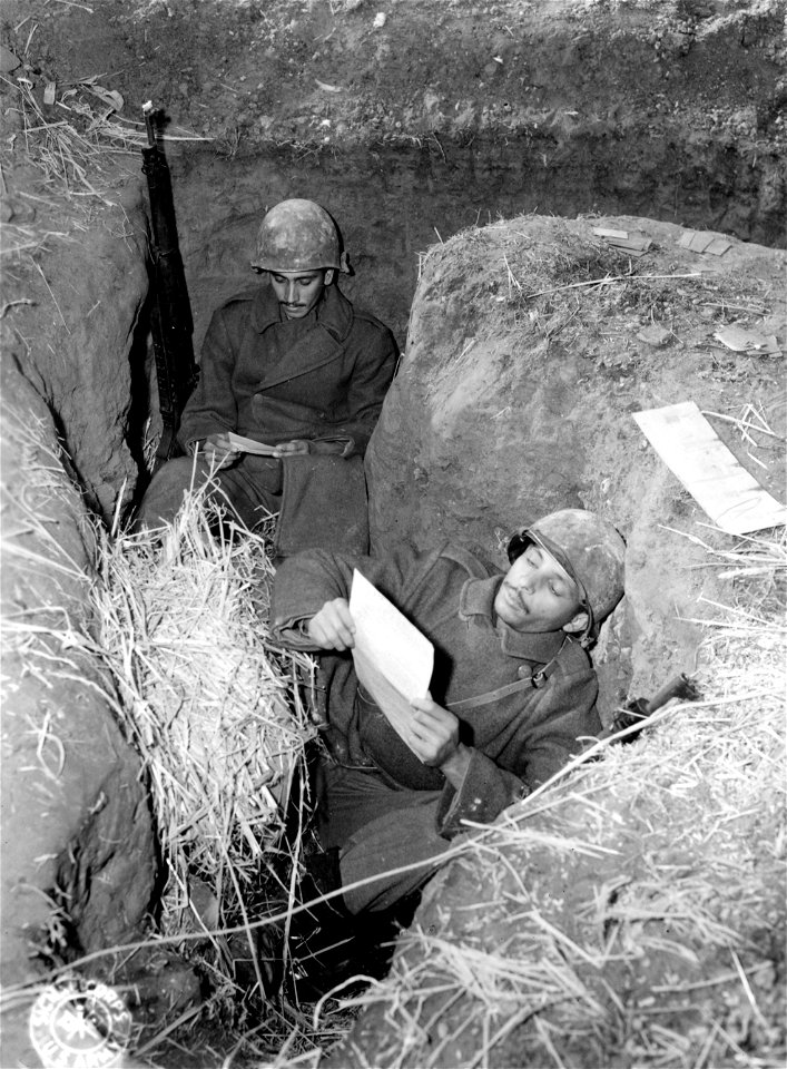 Brazilian infantrymen take time out to read their mail in foxholes on the Italian front.