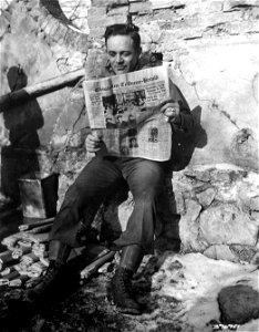 SC 396921 - Cpl. Joe Stainiger, 114 Tener Ave., Chrisholm, Minn., relaxes briefly from his duties as a member of artillery battalion, 34th "Red Bull" Division, to read a copy of his hometown newspaper. 26 January, 1945. photo