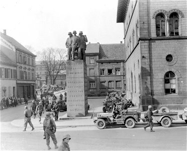 SC 335277 - 3rd U.S. Army soldier guards German prisoners in the public square at Kaiserslautern, Germany. 21 March, 1945.