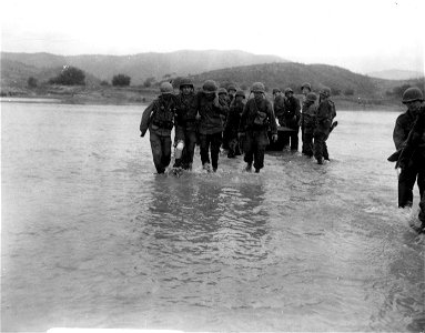 SC 348675 - An American infantryman, wounded during the crossing of the Naktong river, in Korea, is helped ashore, as more seriously wounded follow in a shallow boat. 19 September, 1950.