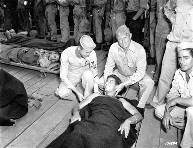 SC 171694 - First Island Command, New Caledonia. Pfc. R. J. Tice, 2nd Marines, with both legs blown off by mortar fire smiles cheerfully at Chief Petty Officer R. E. Hughes, medical unit, as he is landed at New Caledonia...