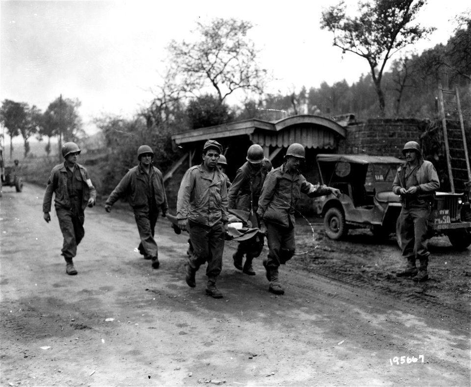 SC 195667 - Under shelling by Nazi units, these Yank medical men carry American wounded to an aid station through the streets of Brouvelieures, France. 25 October, 1944.