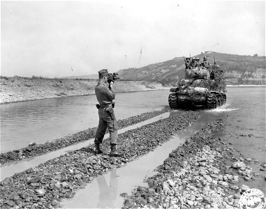 SC 329872 - T/5 John Pitts, Cleveland, Ohio, a motion picture cameraman with the Army Pictorial Service, photographs the first South African tank to cross the Reno River on its way to Bologna. 20 April, 1945. photo