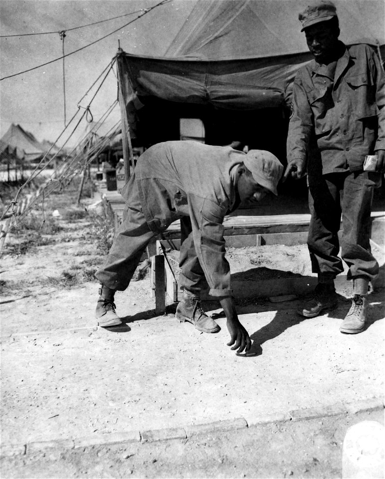 SC 364379 - S/Sgt. Jacobs E. White, RT 4 Sumter, S.C., pulls his rank on his twin brother, Cpl. Benjamin S. White, by getting him to police up the area at Camp Atlanta near Chalons, France.
