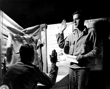 SC 195511-S - L-R: 1st Lt. Wm. M. Norton, Grandview, Tex., voting officer of Co. K, 147th Inf., administers the oath to Pfc. Robert K. Mansfield, Imperial, Neb. photo
