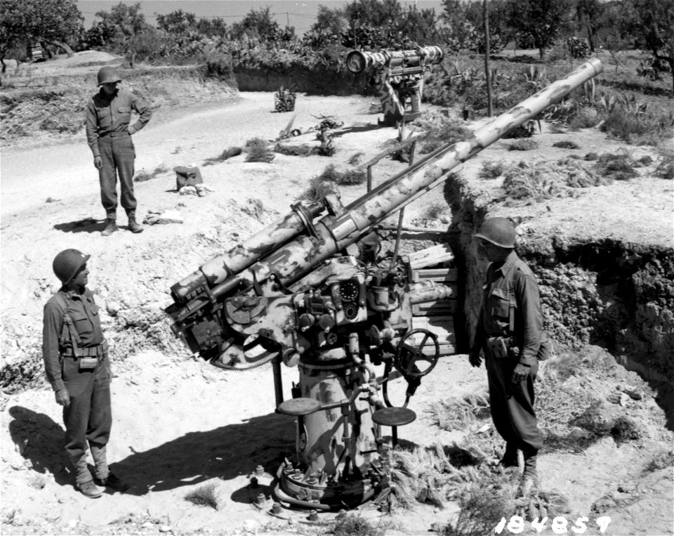 SC 184589 - Major D. A. Heath, Wellesley, Mass, and Lt. Col. Harry L. Campbell, Yale, Mich., ordnance officers in the 1st Division, inspect a captured Italian 75mm antiaircraft near Pt. Oliva Airport, Sicily.