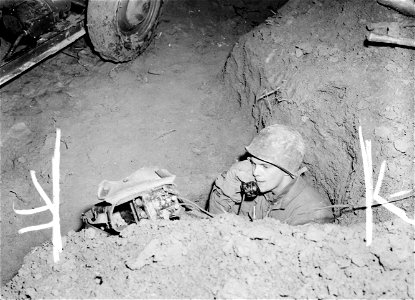 SC Pfc. A. Carol Unrath, Hatbourgh, Pa., crouches in foxhole next to searchlight being used for first time in the 3rd U.S. Army area at the Moselle River near Canach, Luxembourg. photo