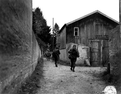 SC 270628 - Members of "I" Co., 7th Inf. Regt., 3rd Division, move up an alley to screen their movement from German observation, as they go toward the edge of the town. photo
