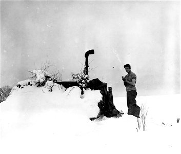 SC 199080 - Pfc. Wiley H. Branch, Huntsville, Ala., member of C Battery, 30th Infantry Division, washes up outside his snow-covered dugout on a front in belgium. 9 January, 1945.