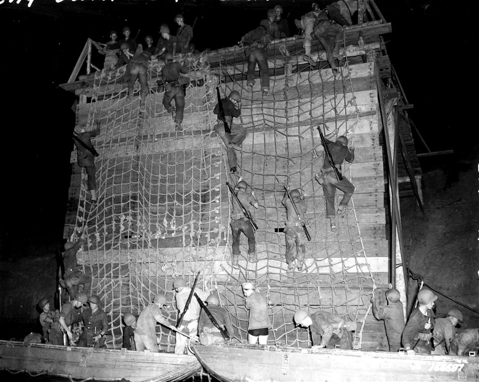 SC 166687 - Riflemen climb down landing nets into assault boats during a night problem. Rockhampton, Australia. 19 November, 1942.