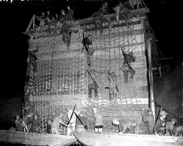 SC 166687 - Riflemen climb down landing nets into assault boats during a night problem. Rockhampton, Australia. 19 November, 1942. photo