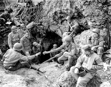 1st Section, Battery B, 158th Field Artillery Battalion, near Pozzilli, takes a break sitting around the natural rock cave in which they live. 18 December, 1943.