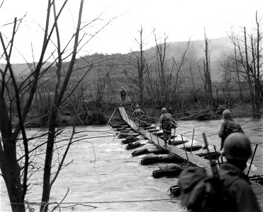 SC 270824 - Men of the 9th Infantry Division cross the Roer River on an infantry assault bridge that was constructed by men of Co. "B", 51st Engineer Combat Battalion.