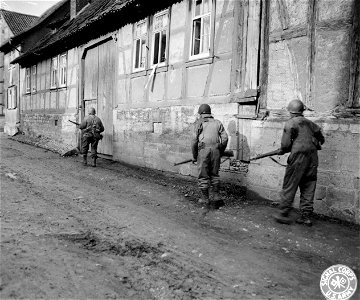 SC 270696 - Infantry troops of Combat Command "A", 6th Armored Division, Third U.S. Army, move cautiously through the outskirts of Muhlhausen, Germany. 4 April, 1945.