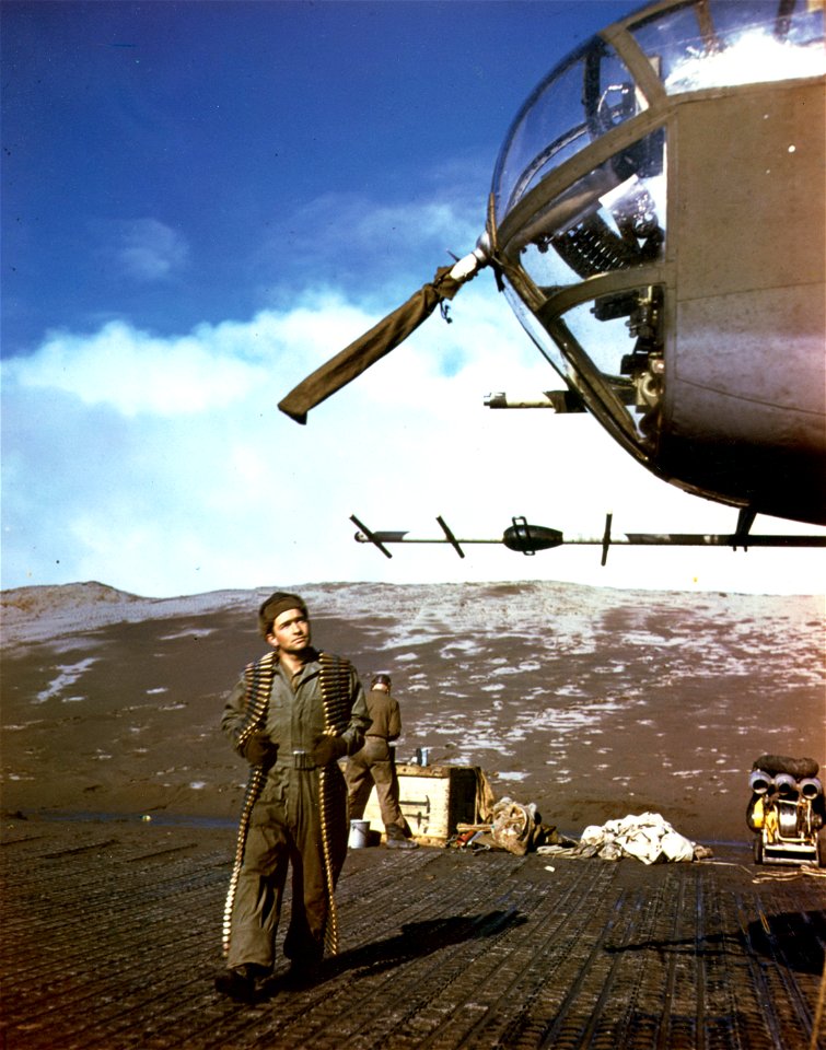 C-912 - Sgt. Clark E. Hillard of Minturn, Colorado, carries metal link ammunition to reload .50 calibre guns on this B-25. Alaska. 1944.
