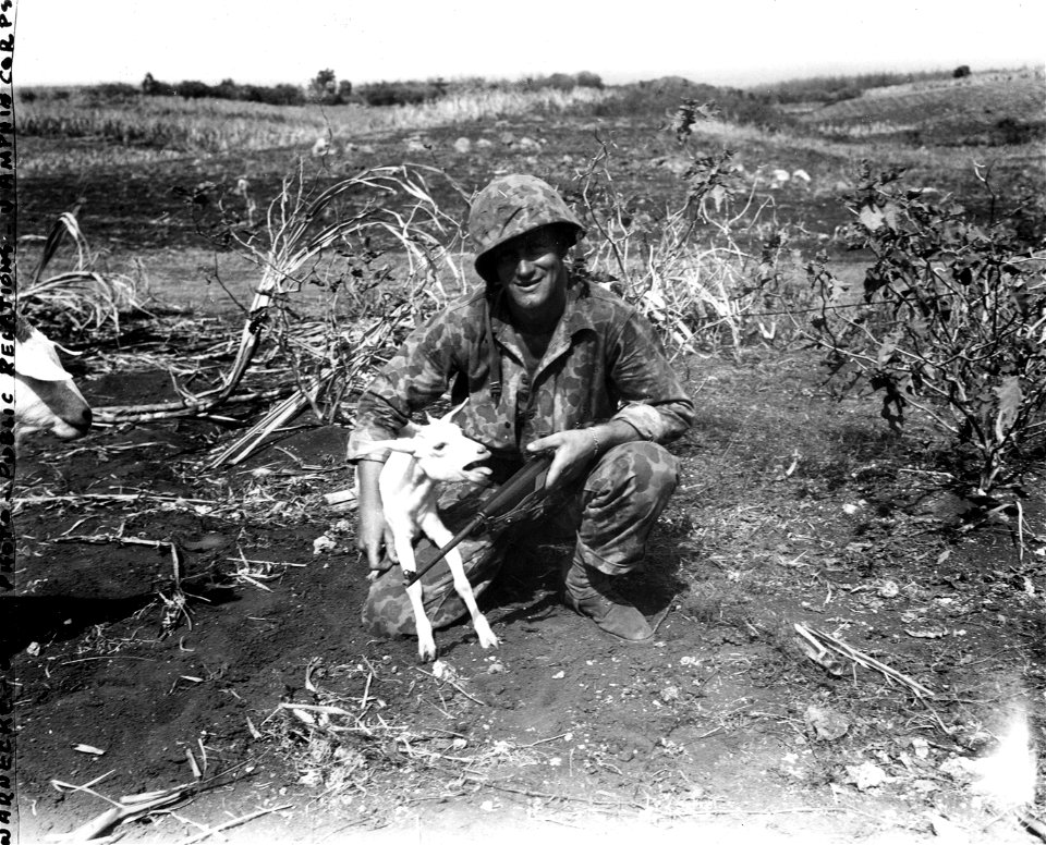 Corporal James F. Allen, 24, son of Mr. and Mrs. Lawrence H. Allen, RFD 1, South Windham, Maine, holds a bleating kid found on Saipan. 7 August, 1944.