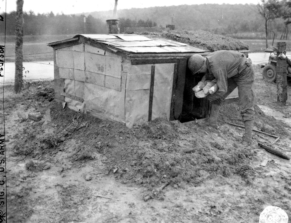 SC 195735 - Cpl. Robert E. Murphy of Cincinnati, Ohio, carries fuel into his homemade shelter near Onville, France.