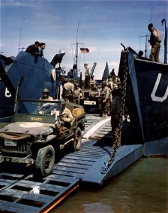 C-1092 - Trucks and Jeeps which will carry men and supplies to the front lines of the Invasion are loaded onto an American landing craft in a British harbor. June, 1944.