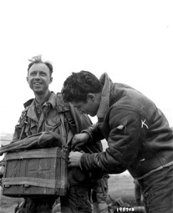 SC 195703 - Preparing for the airborne invasion of Holland, a Yank helps strap equipment on his buddy at a base in England. photo