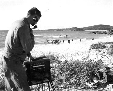 SC 184766 - Lt. Howard Mann of Santa Barbara, Calif., operates a communication set on beach, during amphibious training of 127th Inf. Regt., 32nd Div., in Australia. 12 July, 1943. photo