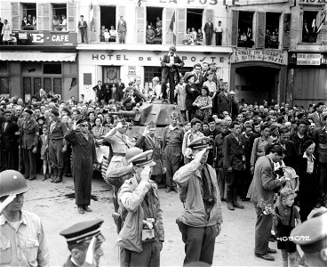 SC 405092 - American Naval officers, in foreground, and French officers, near tank, salute as General De Gaulle is welcomed by residents of the town of Chartres on his first visit to the town since its liberation. 23 August, 1944.