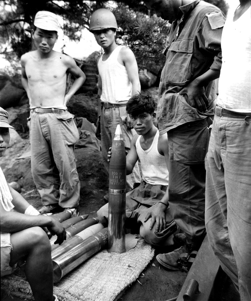 SC 348632 - An ROK soldier of the 15th Regt., 1st ROK Div. shows shells he uses in his 105mm howitzer to fellow soldiers, north of Taegu, Korea. 18 September, 1950.