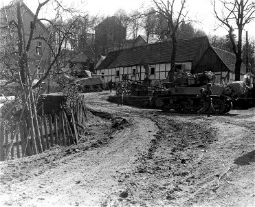 SC 270692 - Tanks support infantrymen of the 5th Division, 3rd U.S. Army, in clearing out a German observation post in the newly-taken town of Grevenstein, Germany. 11 April, 1945. photo