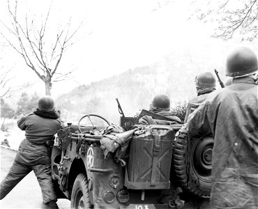 SC 337385 - (409th Task Force photo series) Here, machine gun mounted on jeep, chatters away at enemy positions on the mountains. Man at left with glasses directs fire. 1 May, 1945.