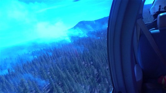 Crew Member Surveys Smokey Forest from a Helicopter