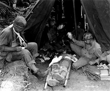 SC 196094-S - Medics administer blood plasma to an American casualty wounded when his division command post was shelled. Leyte Island, P.I. 22 October, 1944. photo