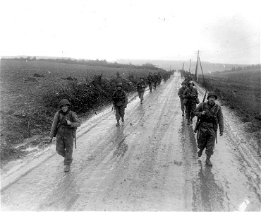 SC 270607 - Infantrymen of the 2nd Division, 1st U.S. Army, move out of Breitenbenden, Germany, down a muddy road leading to their next objective, the German town of Holzheim. 7 March, 1945. photo
