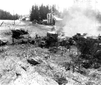 SC 199019 - A 3rd Armored Division halftrack and weapons carrier burns after receiving a direct enemy hit, in the town of Langlir, Belgium.
