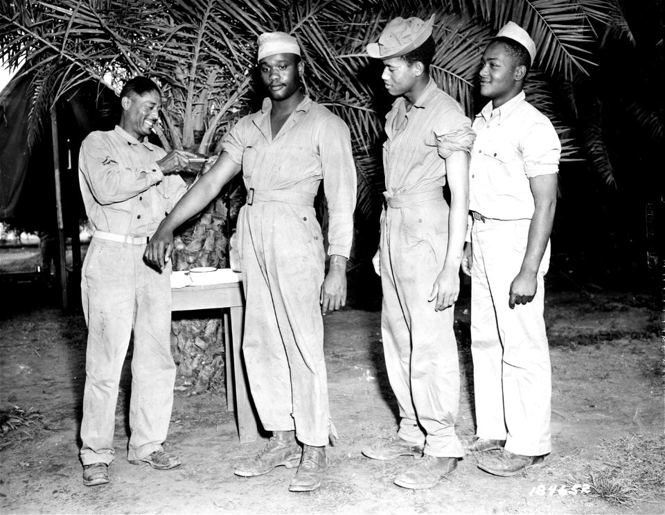 SC 184642 - A "shot" is given to Pvt. Glenn Moore, Warren, Ohio, by T/5 Henry Edwards, member of a Medical Detachment serving in the South Pacific Area.