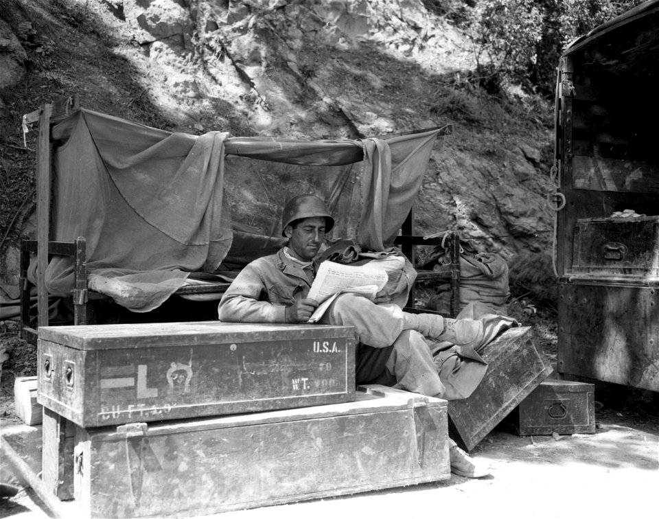 SC 396908 - This soldier, Sgt. William L. Lussy, 1365 Carroll St., Brooklyn, N.Y., relaxes with a Stars and Stripes outside his frontline villa south of Leghorn. 5 September, 1944.